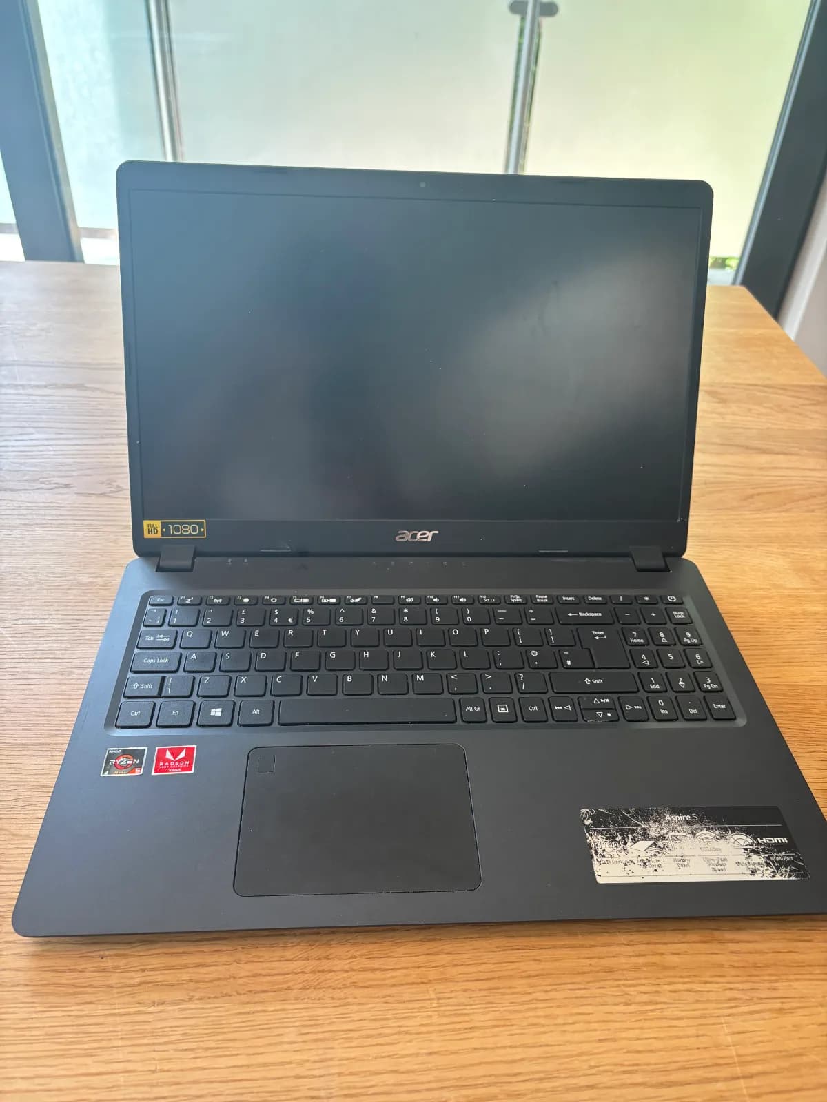 This image shows the front view of the Acer. The Acer has black screen housing, black keyboard, black case and black touchpad with is slightly off-centre.